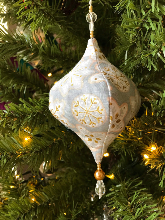 Gold and grey snowflake fabric holiday tree ornament, handmade in Ireland using upcycled fill for sustainable decor.