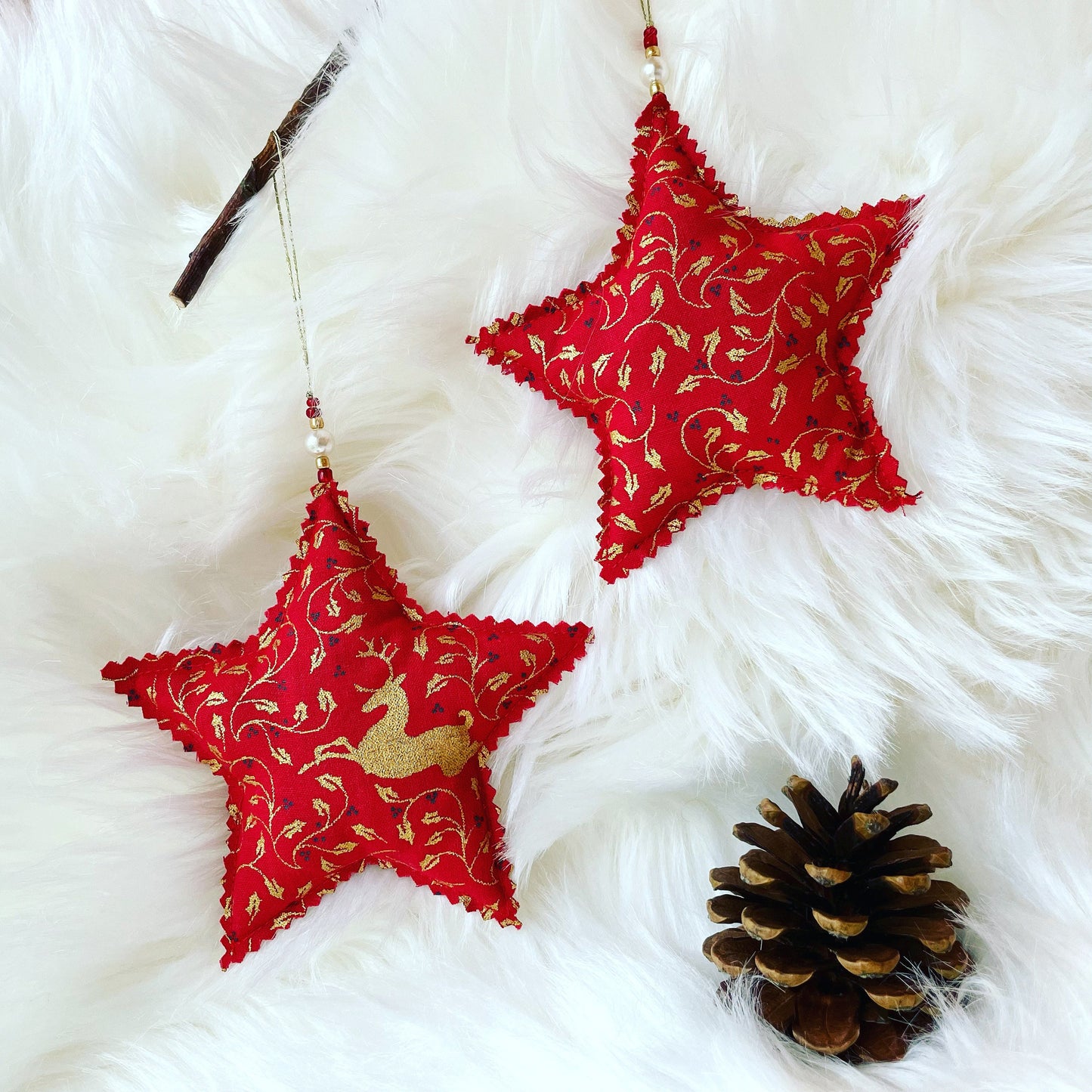 Two red star Christmas tree decorations with a golden deer and holly pattern. Handmade using eco friendly materials.