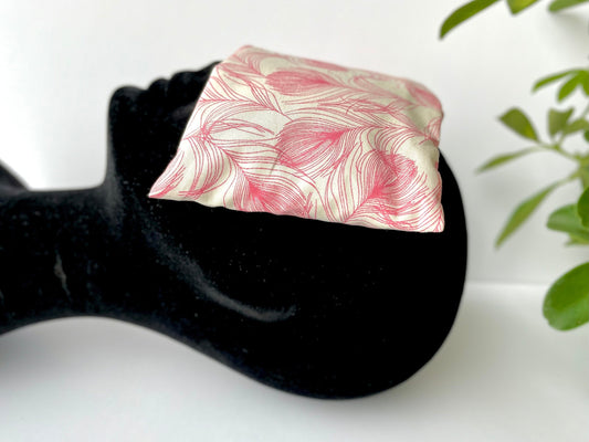 Weighted eye pillow with a pink feather pattern removable cover. Handmade in Ireland with eco friendly fabrics