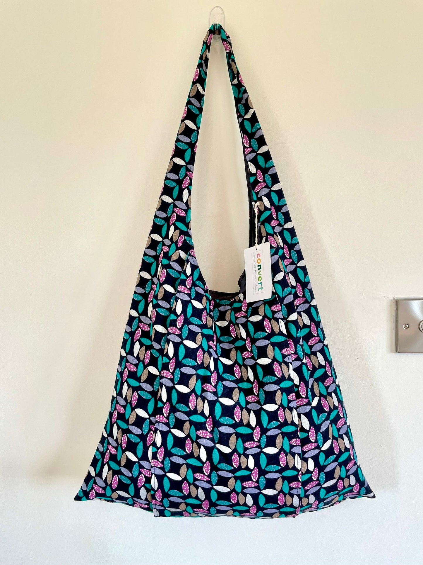 Handmade shoulder bucket bag in a geometric petal pattern fabric in black, green and purples. Made in Ireland.