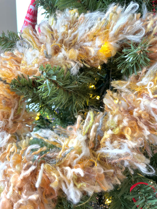 Wool tinsel garland in tones of yellow, gold and white shown on a Christmas tree. Handmade in Ireland
