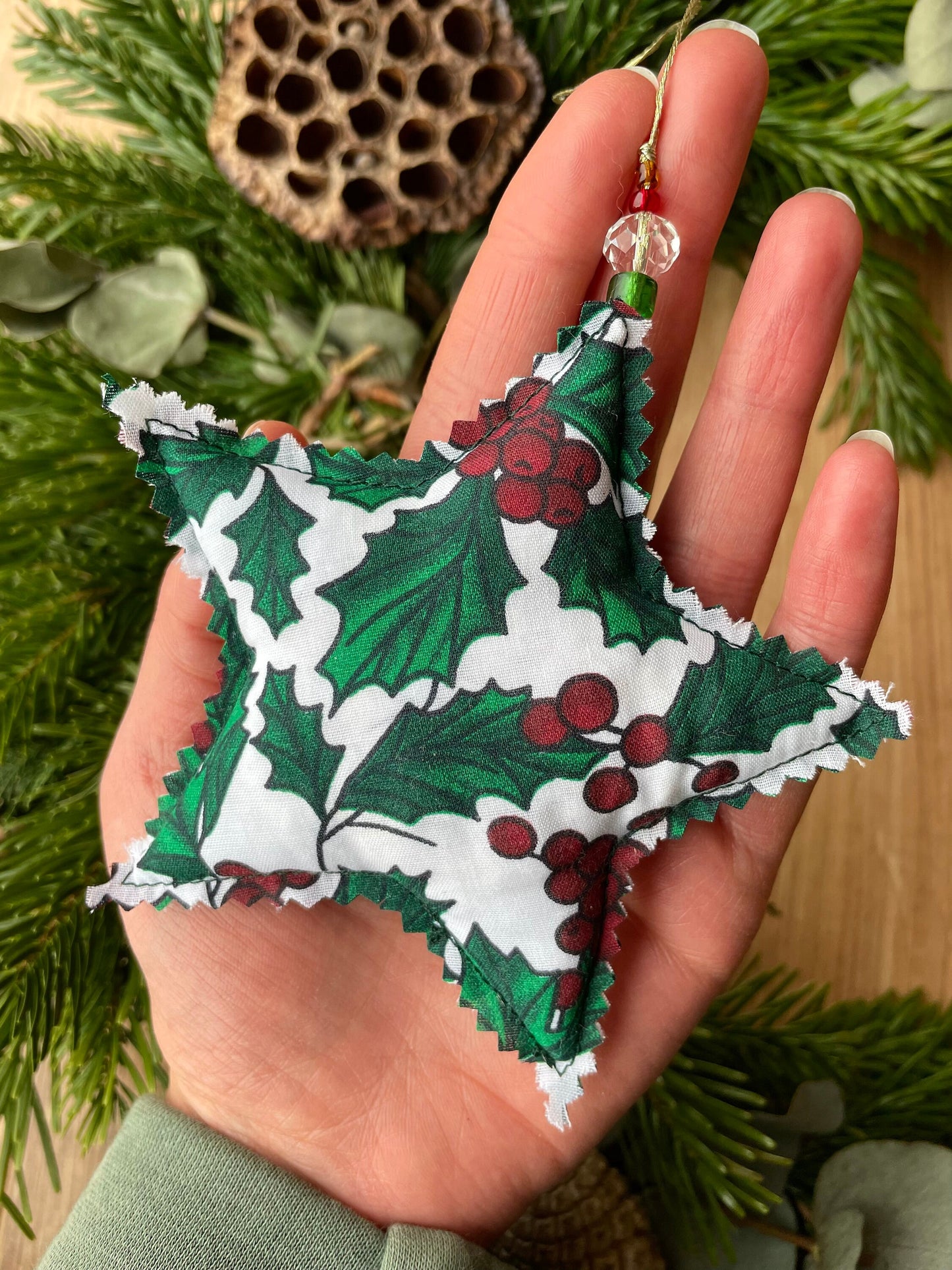 Star shape holly pattern fabric holiday ornament shown in the palm of a hand. Handmade in Ireland