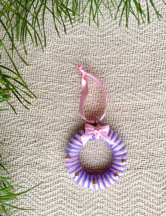 Upcycled wool holiday ornament in pink, purple and white with gold beads. The handmade eco-friendly decoration is in the shape of a mini wreath. 
